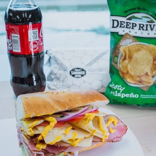Lunch in a bag with a sub, chips and a drink