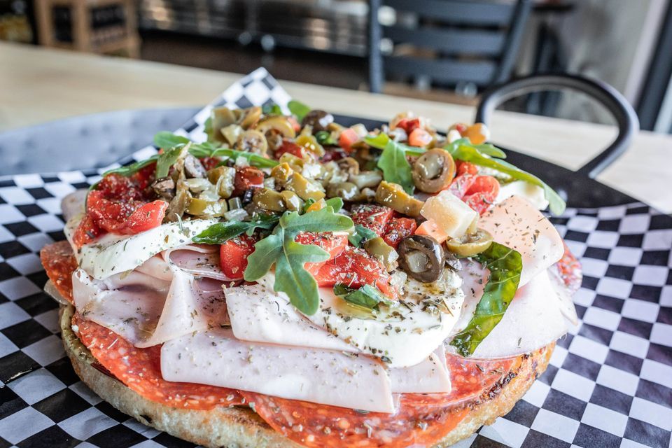 Sub topped with olives, arugula and fresh mozzarella